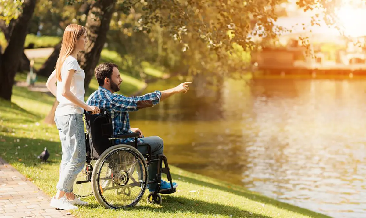 Kobieta i mężczyzna na wózku patrzą na jezioro.