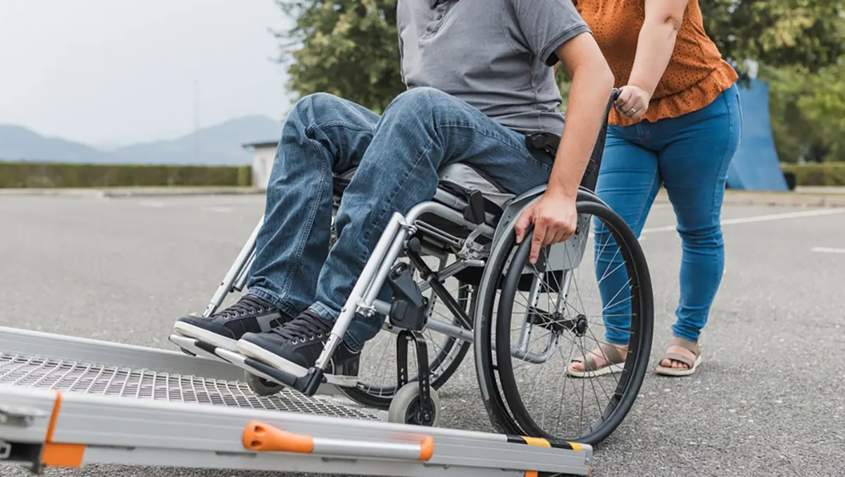 Kobieta pomaga osobie poruszającej się na wózku wjechać na rampę