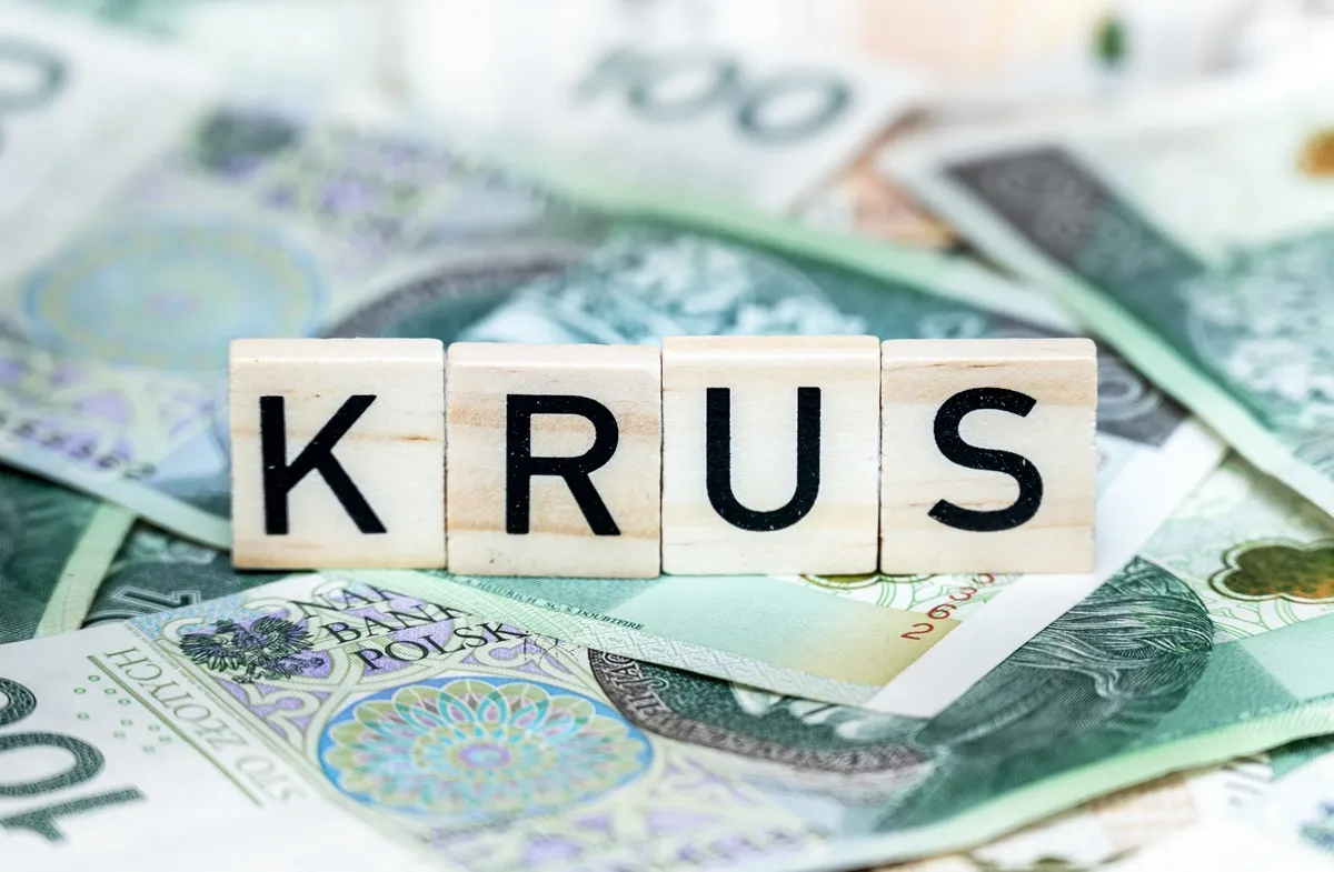 słowo krus ułożone z płytek do scrabble na tle pieniędzy